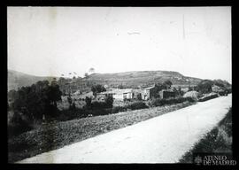 Paisaje con casas, campo y un camino en primer plano