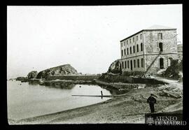 
Vista de la orilla de un mar con edificio y hombre en primer plano
